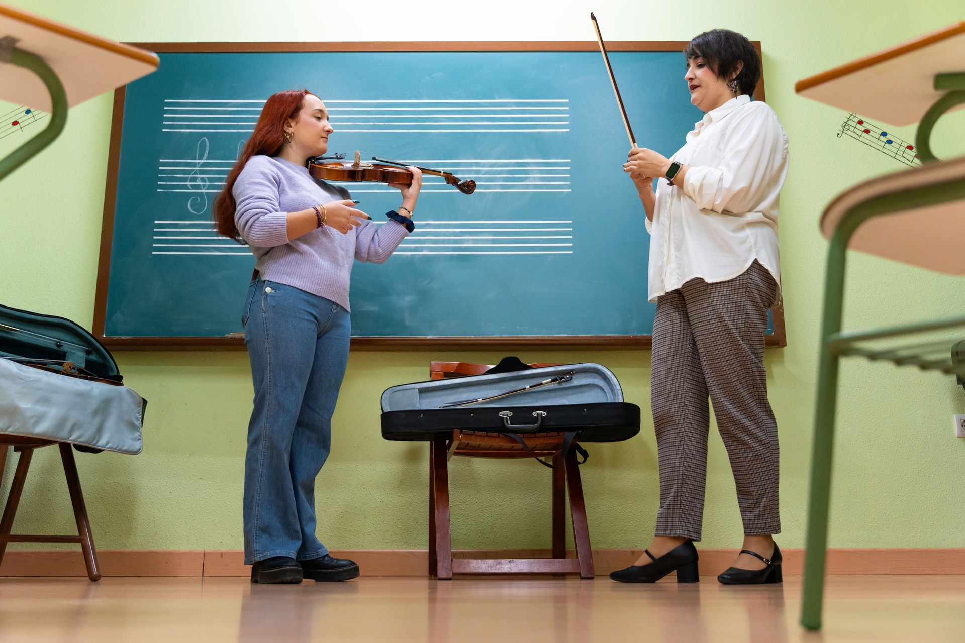 Violin teacher giving private music lesson in classroom