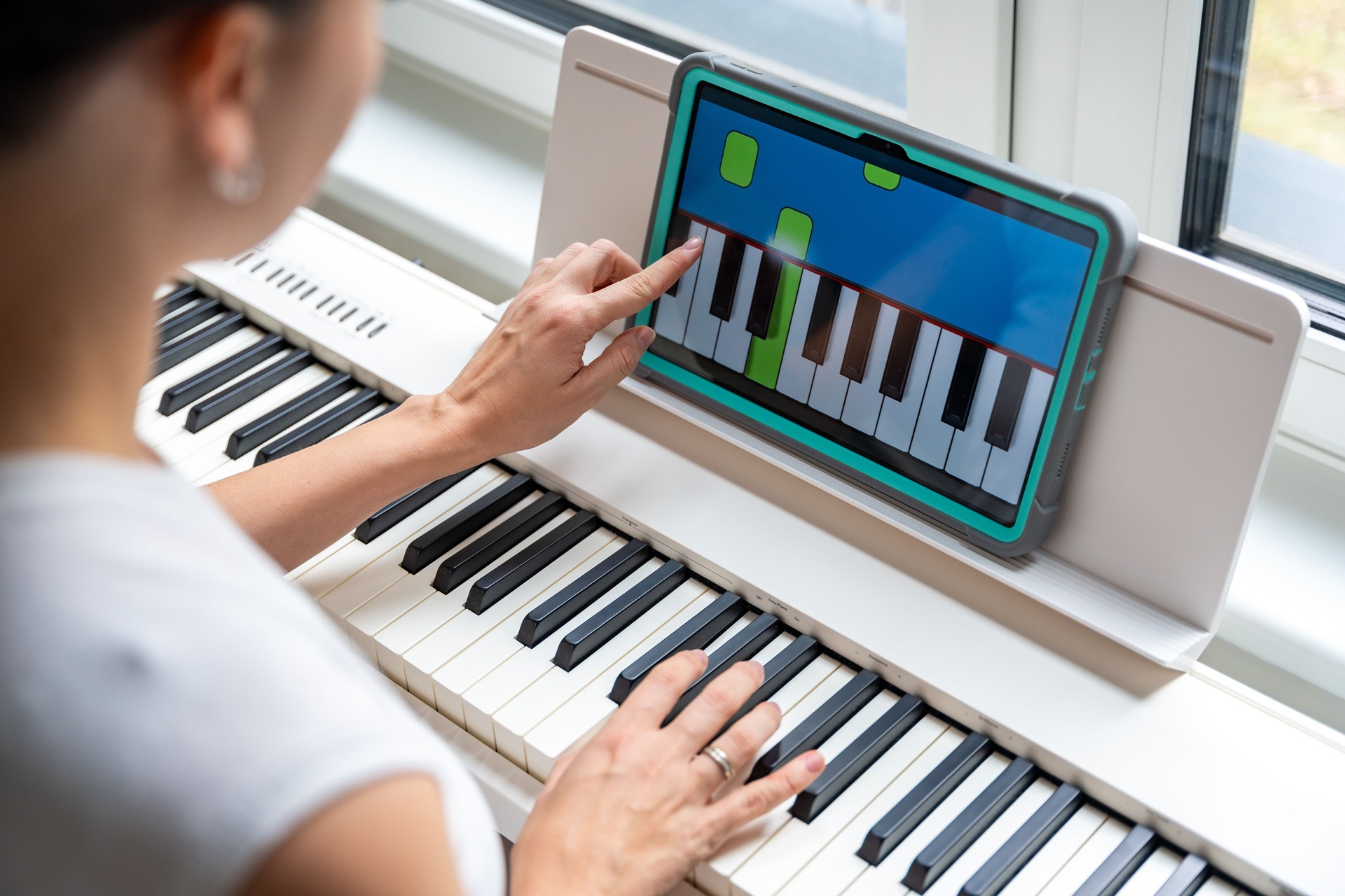 Close up view of young woman learning to play the keyboard at home using an interactive app. Using mobile apps for self-study concept